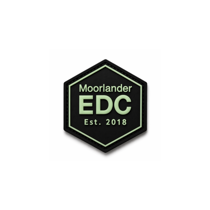 Moorlander x FirmGuards EDC PVC patch with glow in the dark green lettering on black hexagon base, premium morale patch for everyday carry gear